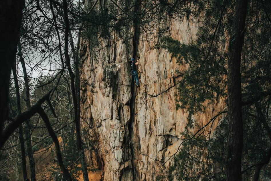 Climber placing a tricam in a granite crack during a sunny multi-pitch ascent