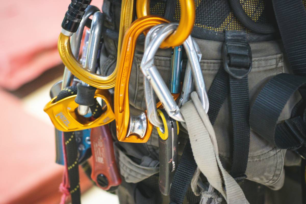 Climber quickly placing a red tricam in a crack with climbing technology easy access gear rack visible on harness